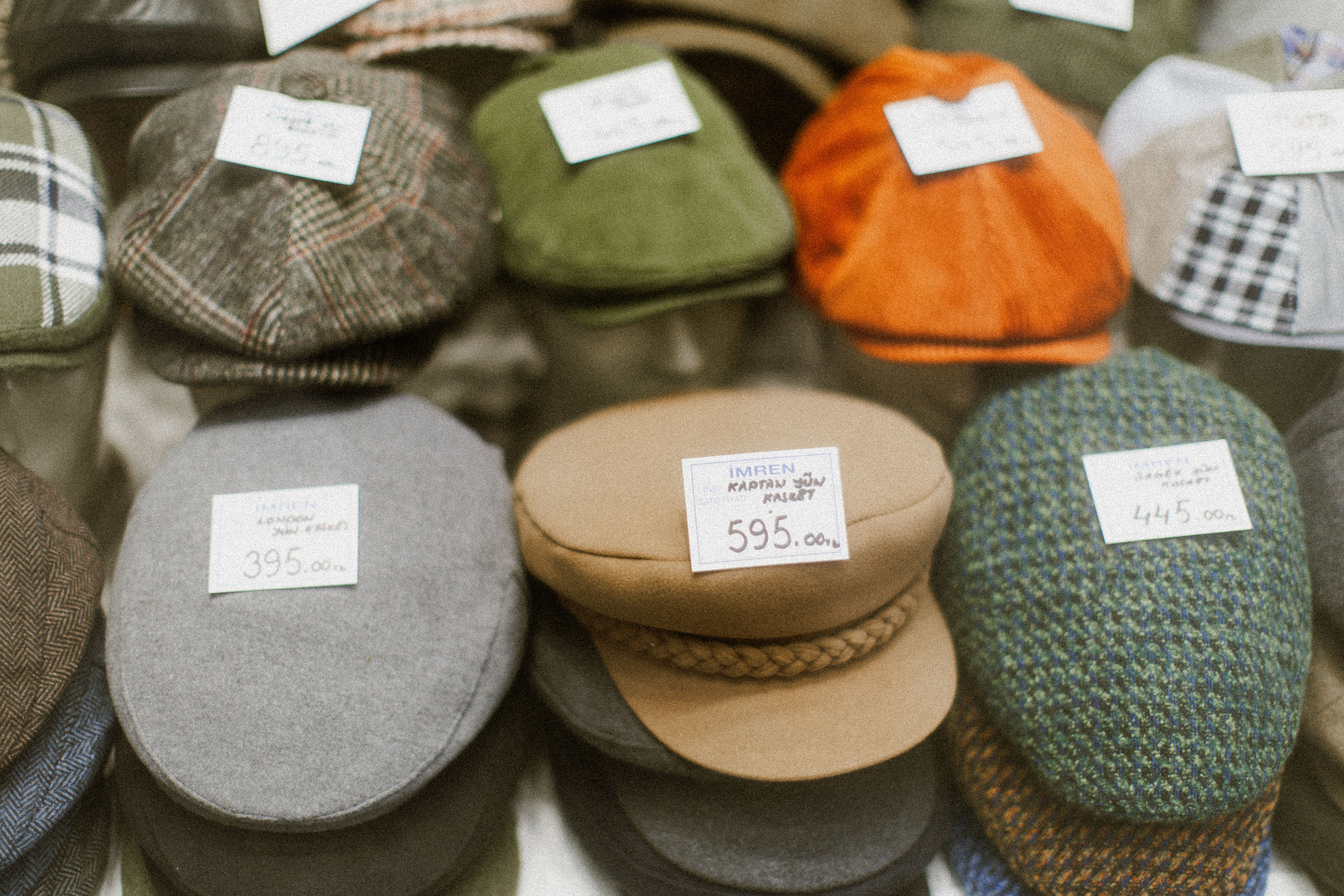 Casquettes plates et casquettes de gavroche vintage présentées avec leurs étiquettes de prix, illustrant la variété des styles et des couleurs.