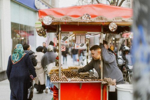 Free A busy street scene in Istanbul with a vendor selling roasted chestnuts, capturing local culture. Stock Photo