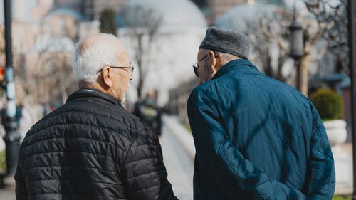 Free Two senior men walking in Istanbul, engaging in conversation on a sunny day. Stock Photo