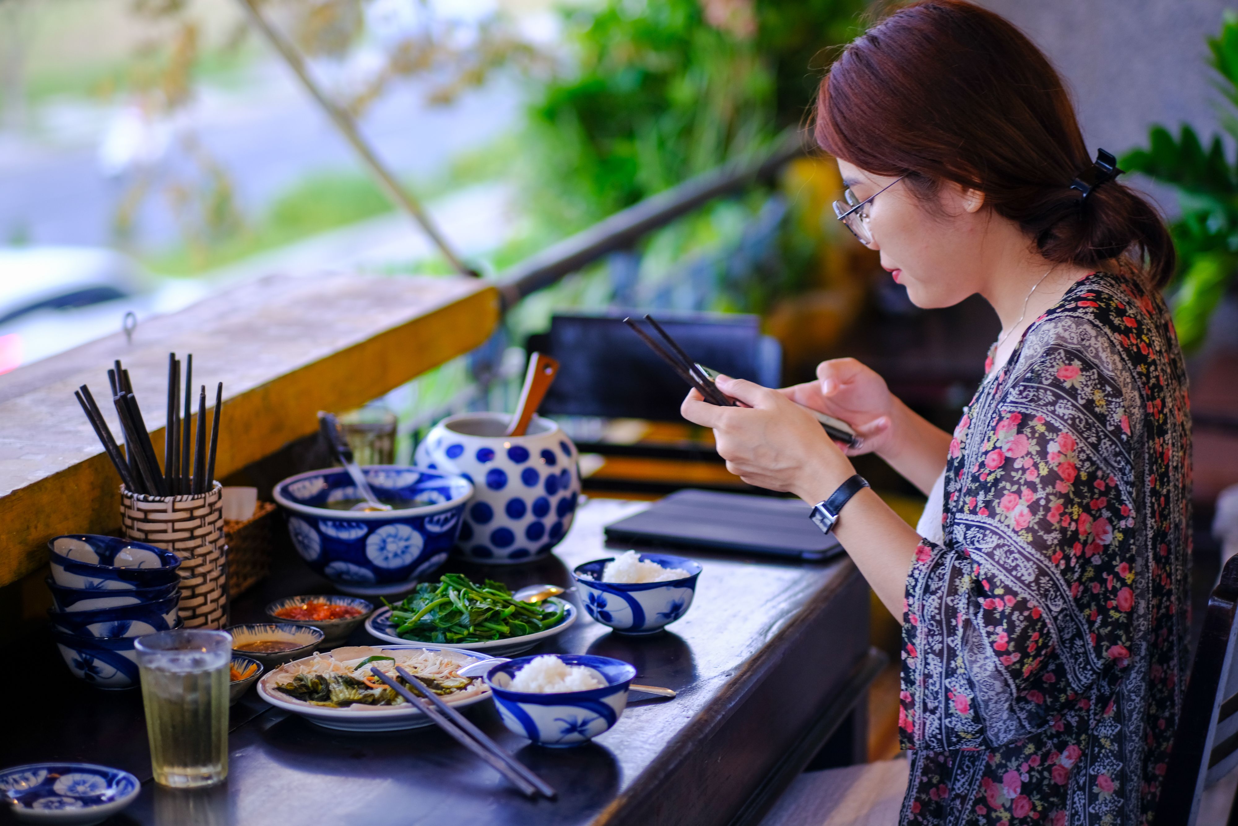 A woman photographs a traditional Vietnamese meal on a balcony in Da Nang, Vietnam.