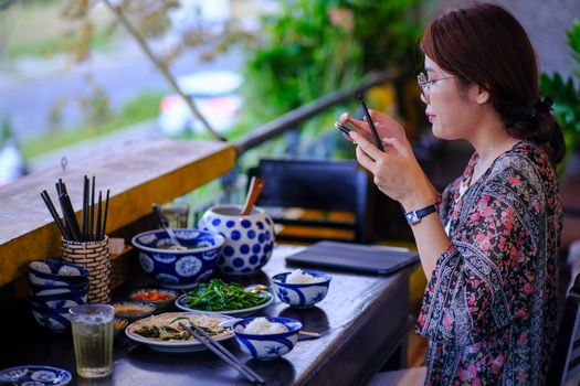 A woman photographs a vibrant Vietnamese meal in a Da Nang restaurant, capturing the essence of local cuisine.
