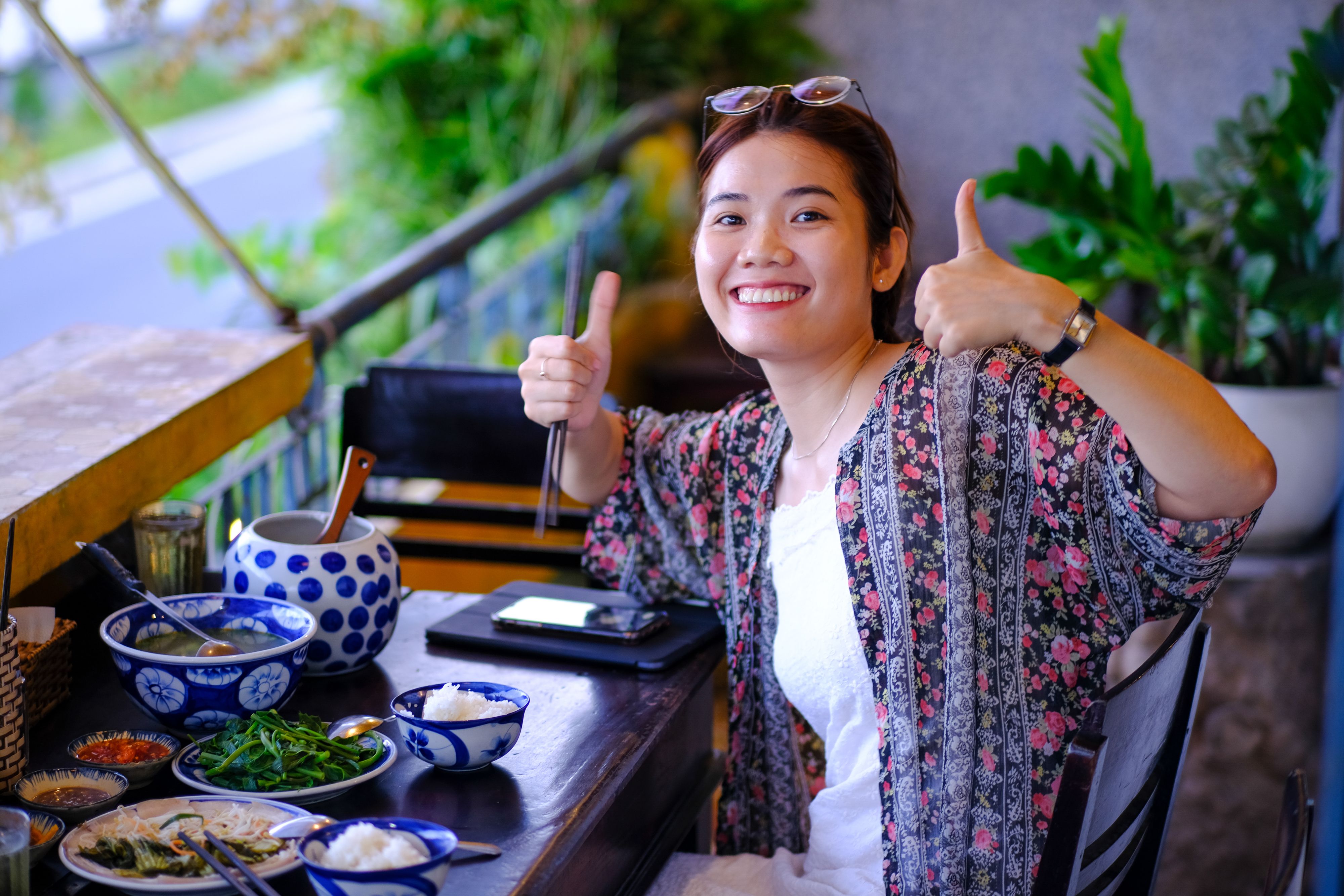 Smiling woman enjoying traditional food in a vibrant atmosphere in Da Nang, Vietnam.