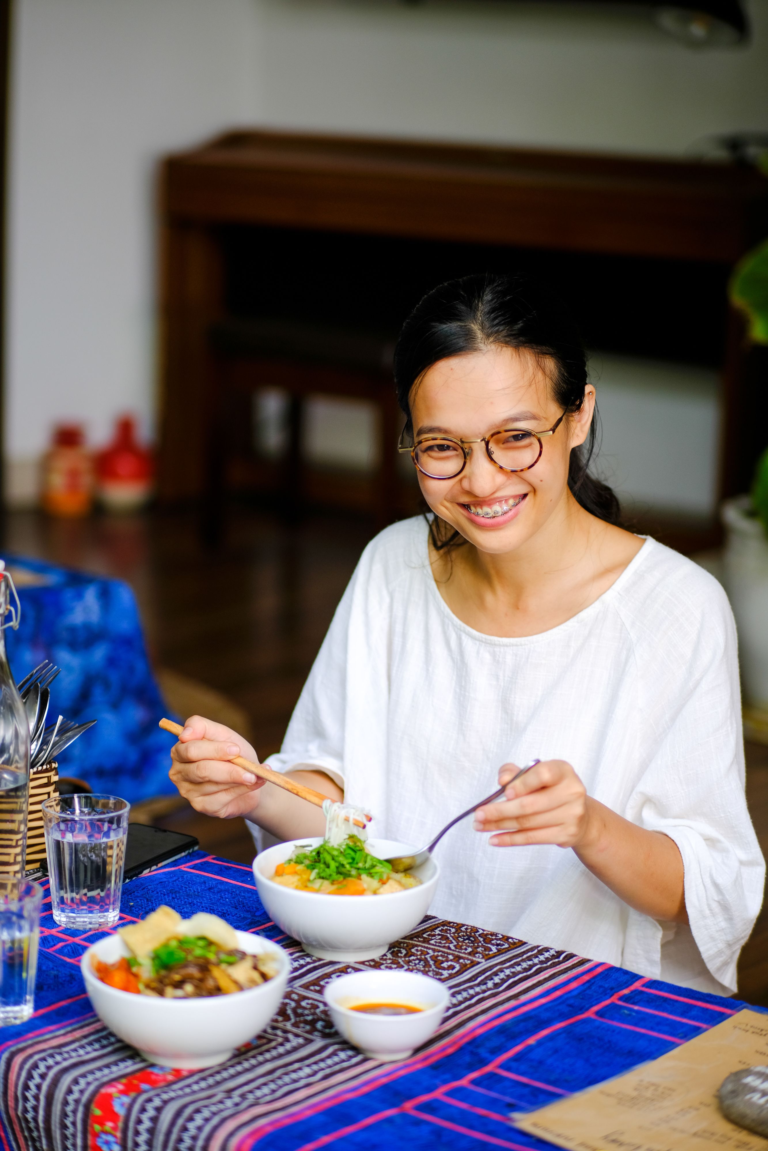 A woman enjoys a traditional Vietnamese meal indoors, creating a warm ambiance.