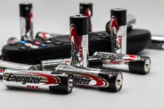 Close-up of multiple Energizer AA batteries and a remote control on a white surface.