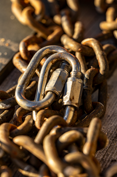 Detailed view of a rusty chain with a metal link, highlighting texture and contrast.