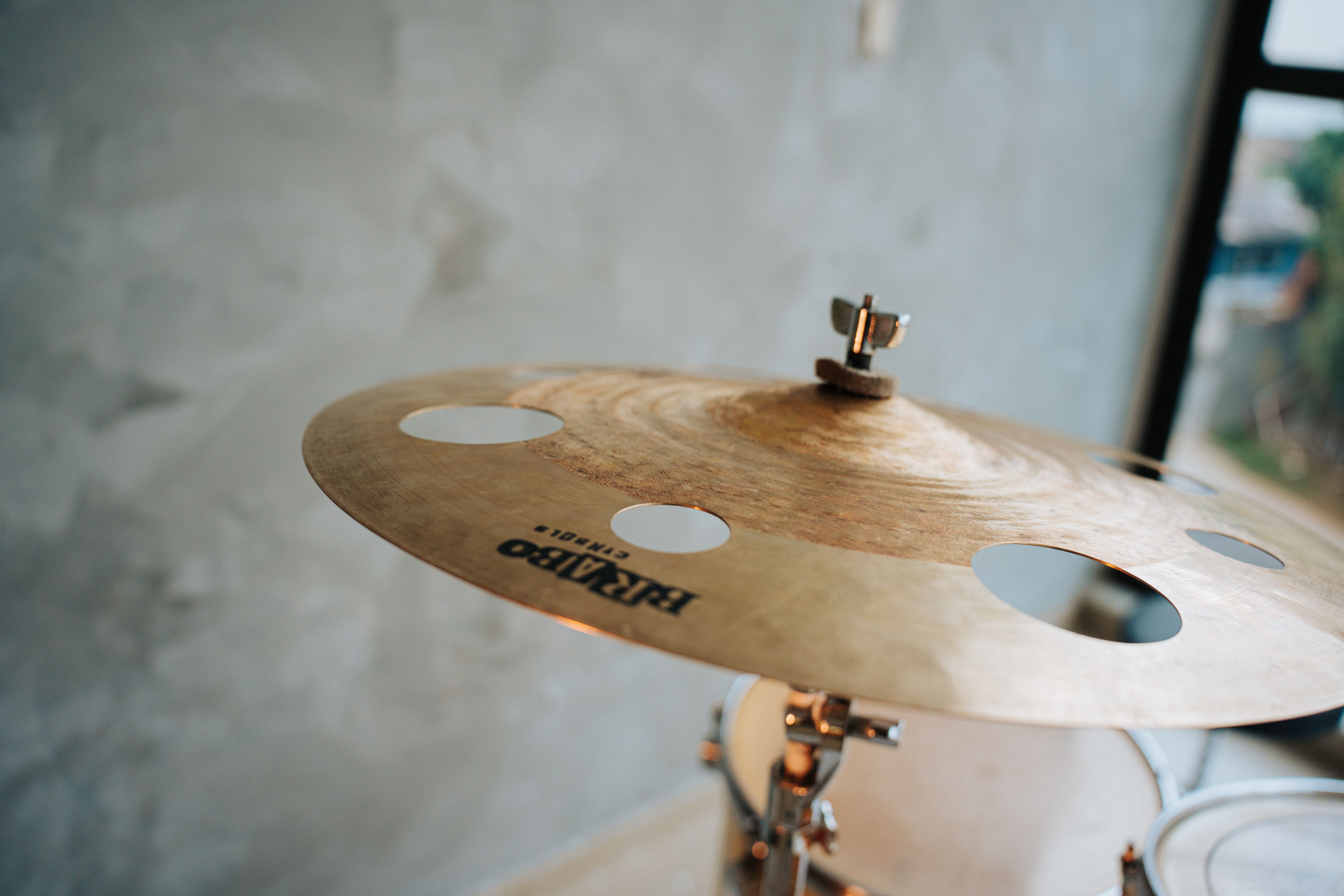 Detailed view of a cymbal in a minimalist indoor music studio, offering a warm ambiance.