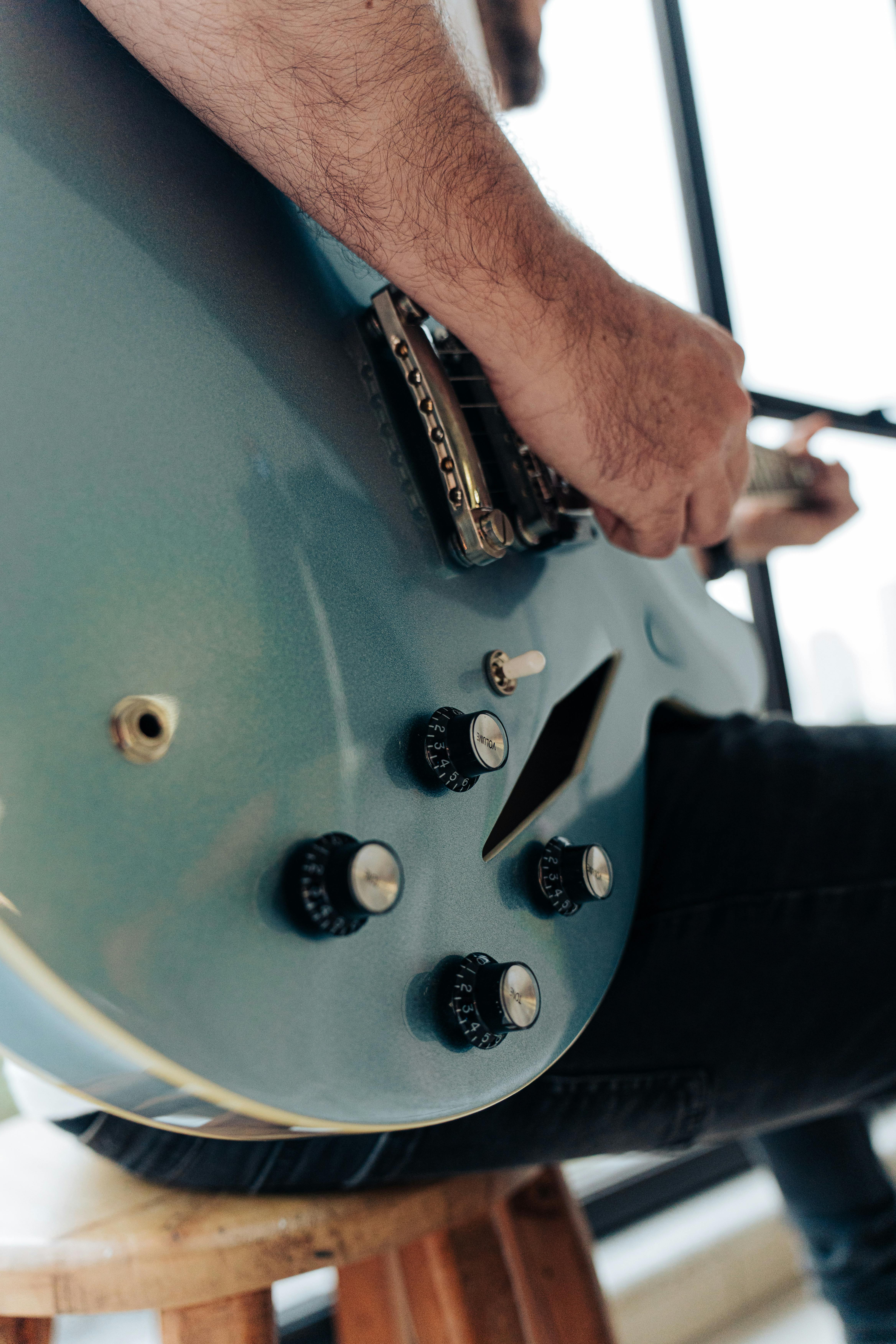 A detailed shot of a musician playing a blue electric guitar indoors.