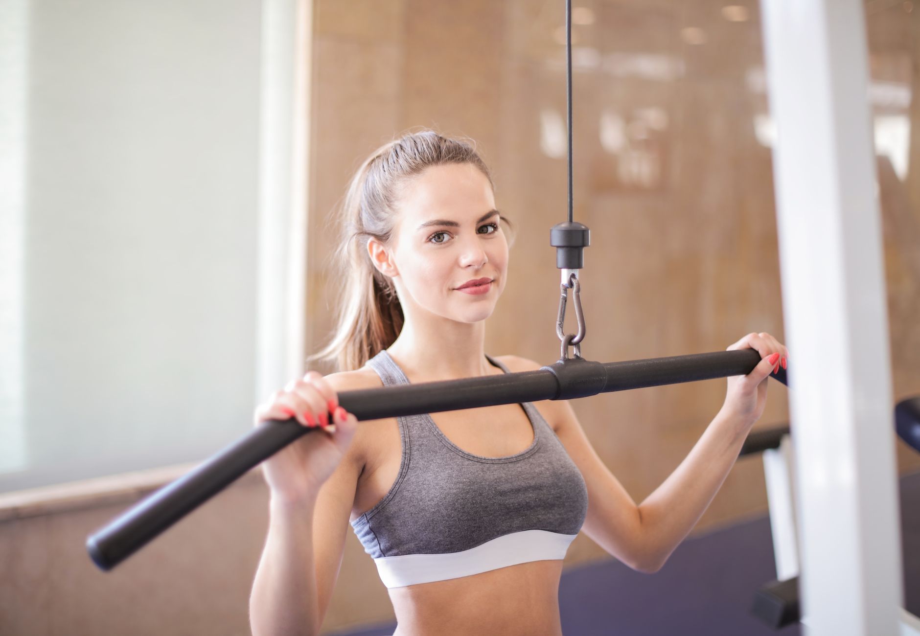 Young woman using gym equipment for strength training in a modern fitness facility.