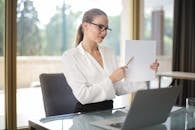 Determine female executive manager in formal wear sitting at table with laptop in office and explaining business plan