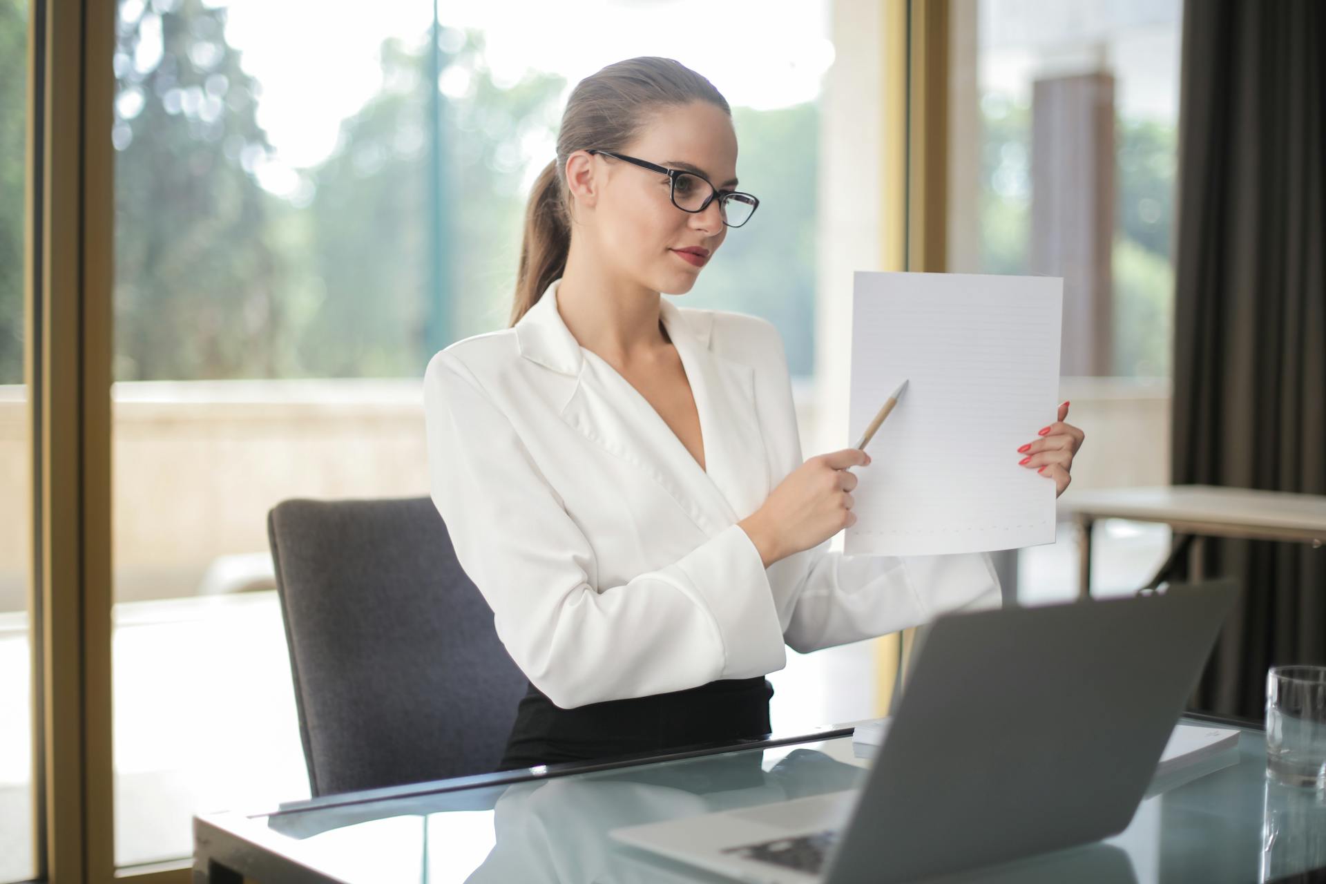 Determine female executive manager in formal wear sitting at table with laptop in office and explaining business plan