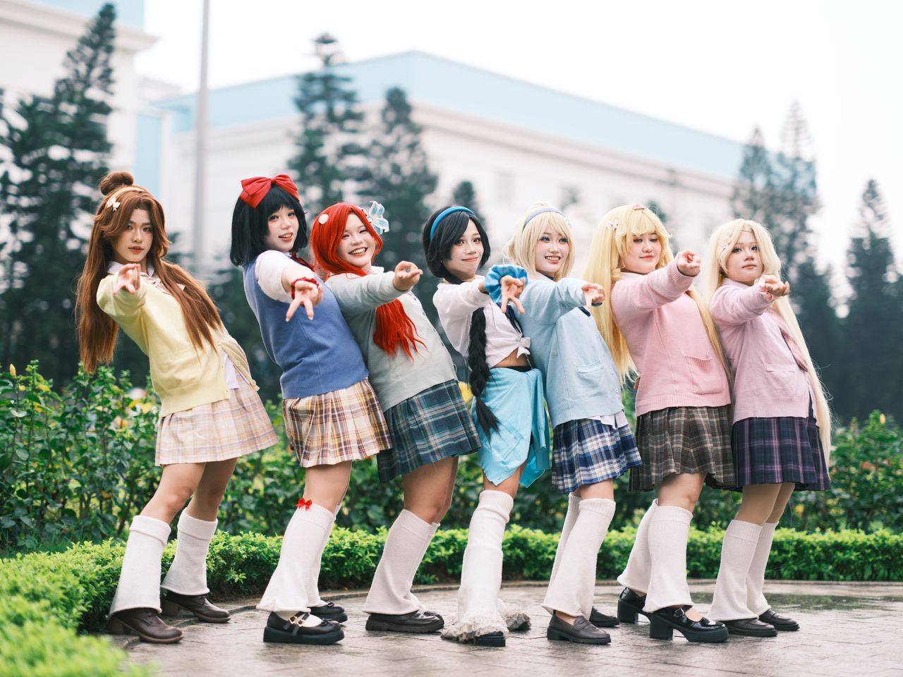 seven young cosplayers pose in colorful anime inspired costumes outdoo