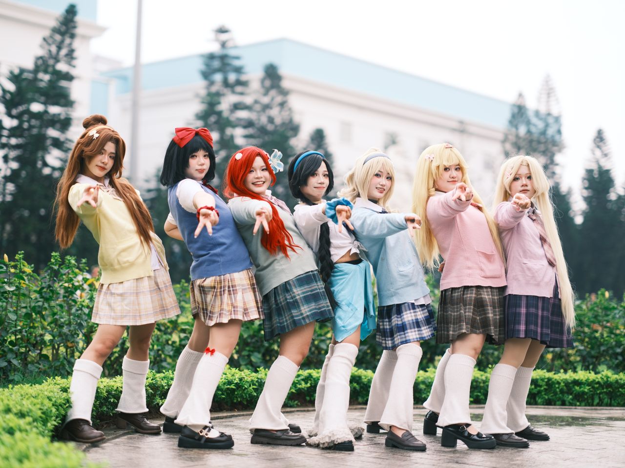seven cosplayers in colorful costumes pose together outdoors showcasin
