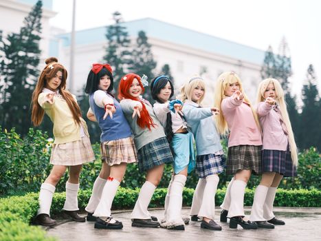 A vibrant cosplay group in colorful school uniforms posing outdoors with cheerful expressions.
