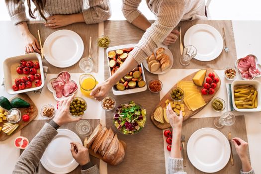 Overhead view of a diverse cheese platter setup for a delicious meal, featuring fresh produce and juices on a table.