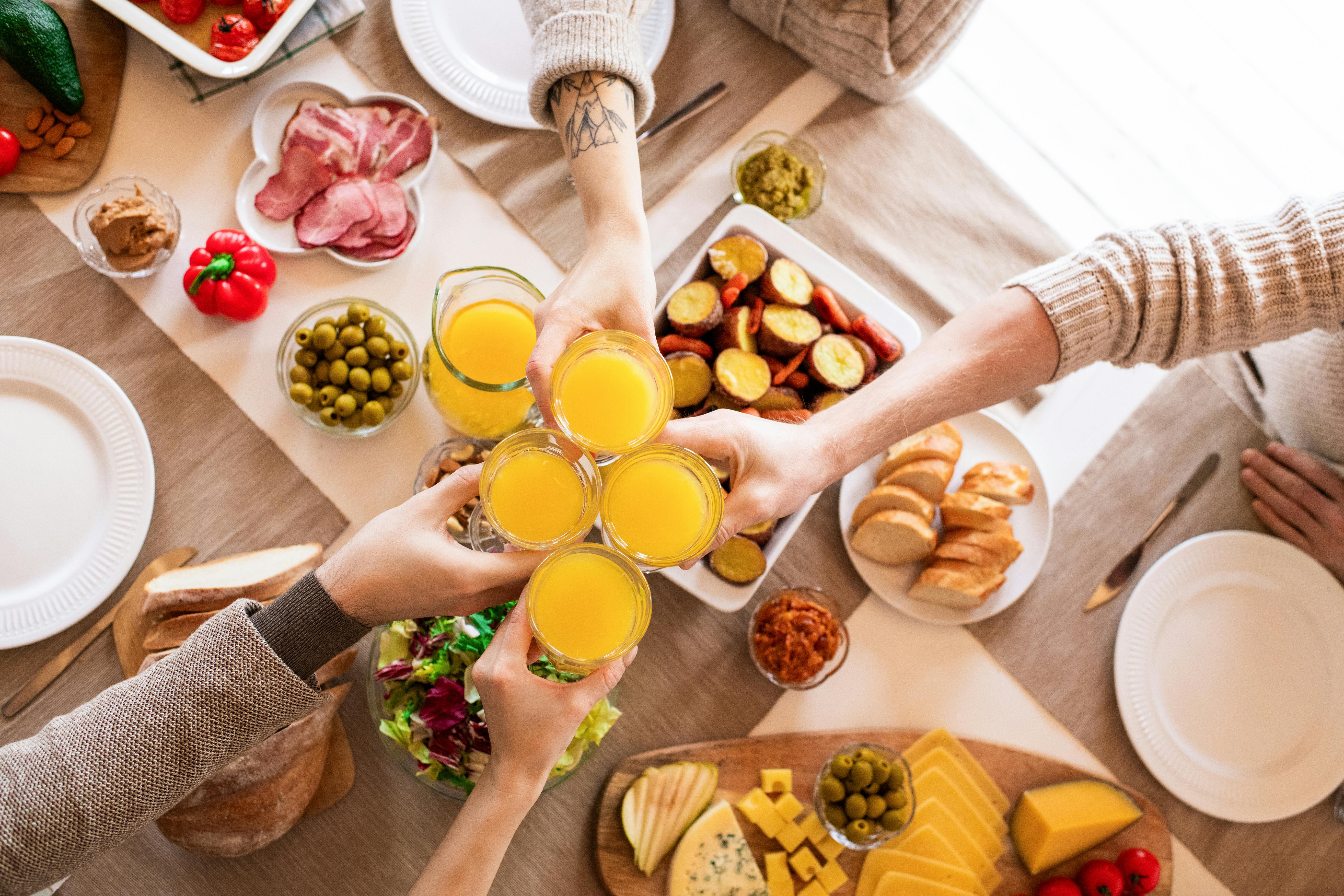 Free People Holding Orange Juice Filled Drinking Glasses Stock Photo