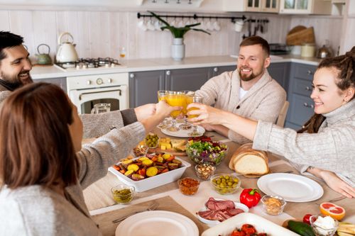 Free Group of friends enjoying a joyful meal together at home, sharing laughter and food. Stock Photo