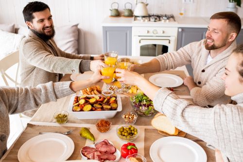 Free A joyful group enjoying a meal together, sharing smiles and drinks around a cozy dining table. Stock Photo
