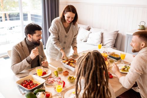 Free Smiling friends enjoy a delicious indoor brunch with fresh fruit and conversation around a table. Stock Photo