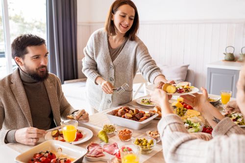 Free A warm indoor gathering of friends enjoying a meal with diverse dishes on a table. Stock Photo