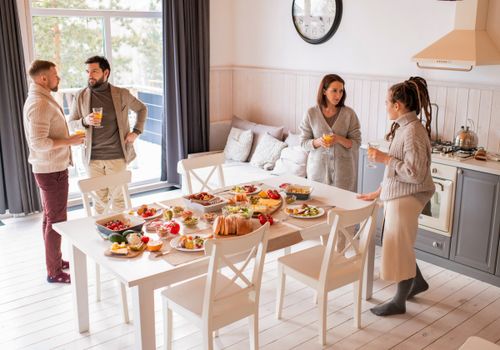 Free A cozy indoor breakfast with friends enjoying a variety of foods and orange juice. Stock Photo