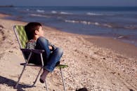 一个小男孩坐在海边的沙滩椅上，享受着夏日的宁静