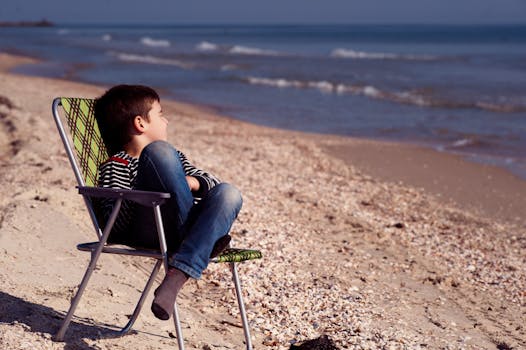 一个小男孩坐在海边的沙滩椅上，享受着夏日的宁静