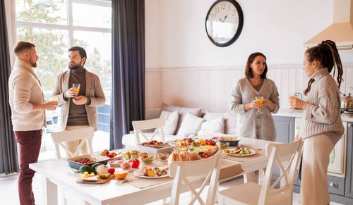 Free Friends enjoying a cozy brunch indoors with a full spread of delicious food and drinks. Stock Photo
