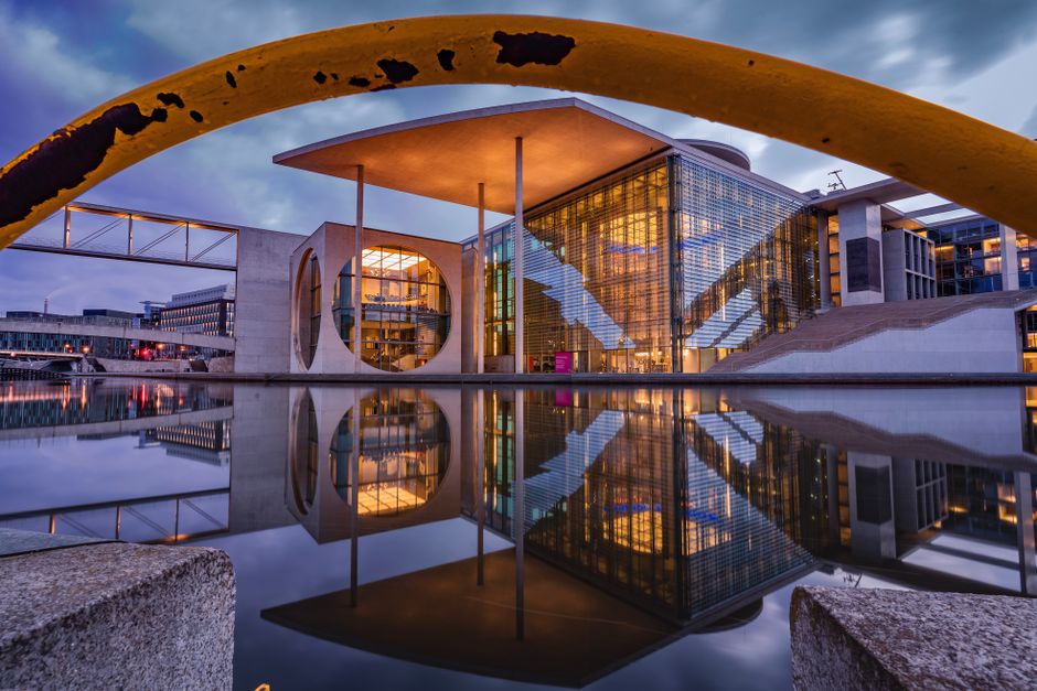 Captivating image of a modern architectural landmark reflecting in water at dusk.