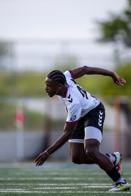 Free Photograph of a male soccer player running on a field, captured during a sports event. Stock Photo