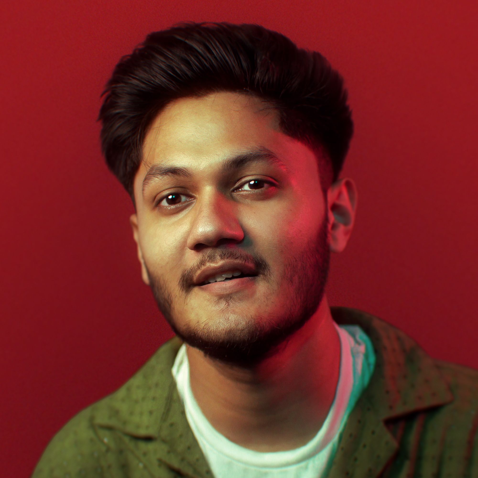 Portrait of a young man against a vibrant red background, looking confident and expressive.