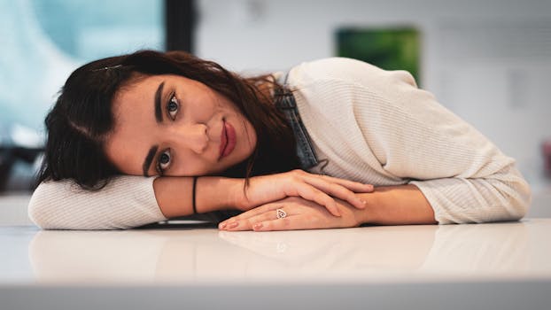 A serene female with brunette hair rests on a table indoors, capturing a calm moment.