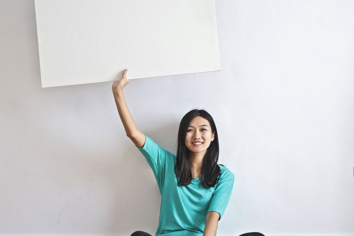 Mulher sentada com caderno fazendo uma pausa tranquila junto à janela