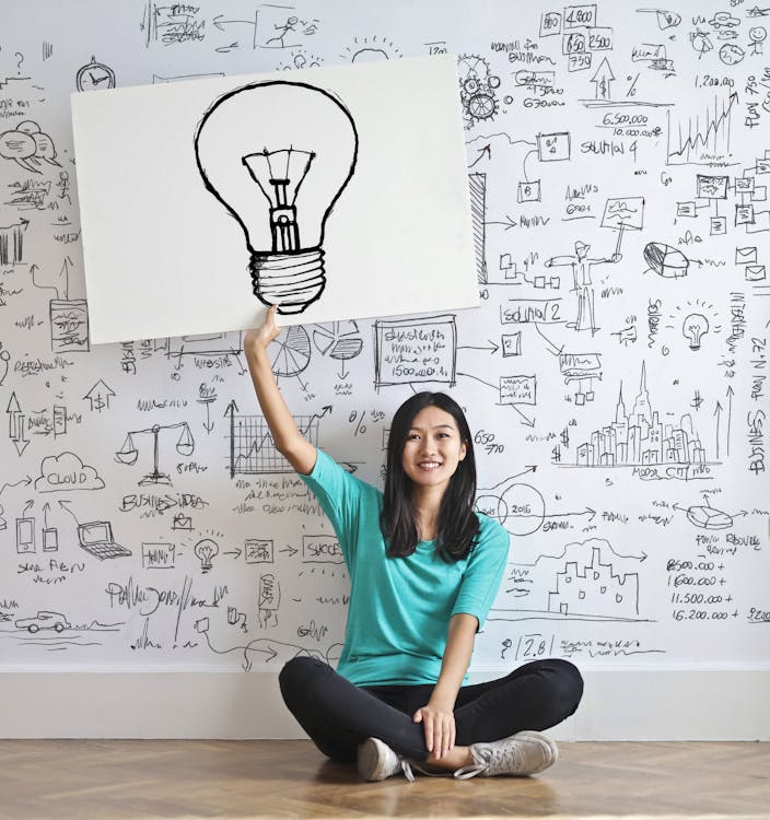 Femme dessiner une ampoule dans un tableau blanc