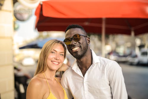 Free Selective Focus Smiling Man in White Button Up Shirt Standing Beside Smiling Woman in Yellow Halter Top Stock Photo