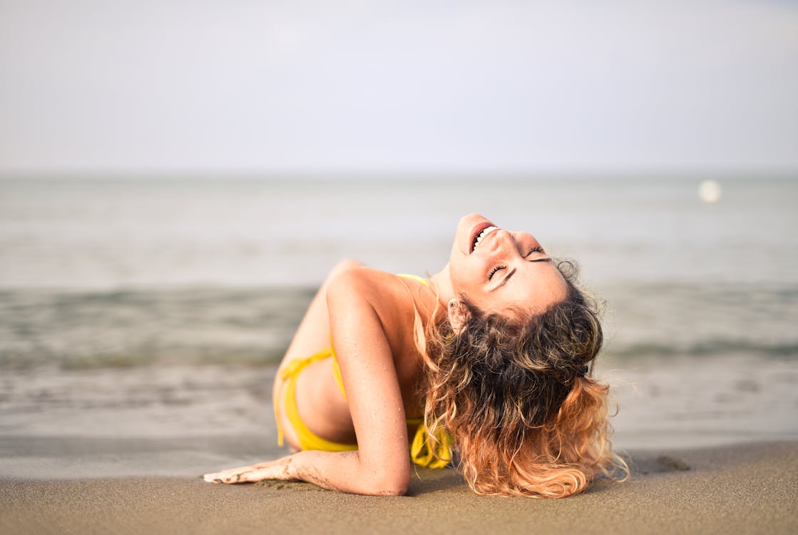 Woman in Yellow Bikini Lying on Seashore