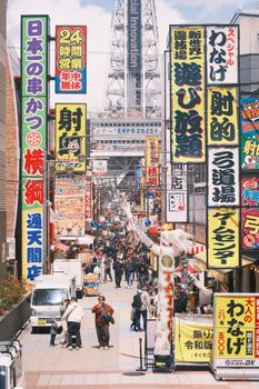 Colorful signs and bustling crowds capture the vibrant energy of Shinsekai District in Osaka, Japan.