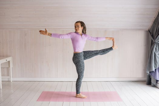 女人在室内垫子上练习瑜伽平衡姿势，以增强柔韧性