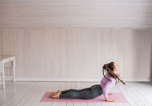Free A woman in activewear performing a yoga pose on a mat indoors, emphasizing fitness and flexibility. Stock Photo