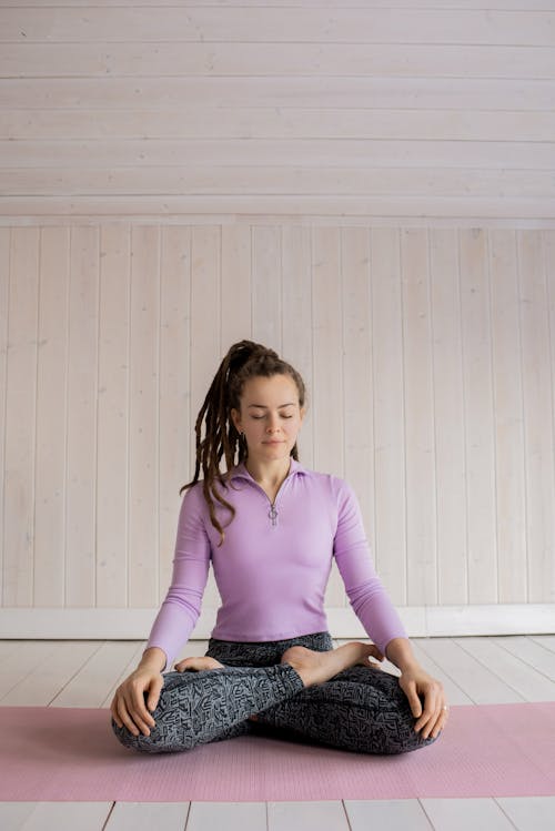 Woman in Purple Long Sleeve Shirt and Black Denim Leggings Sitting on Mat