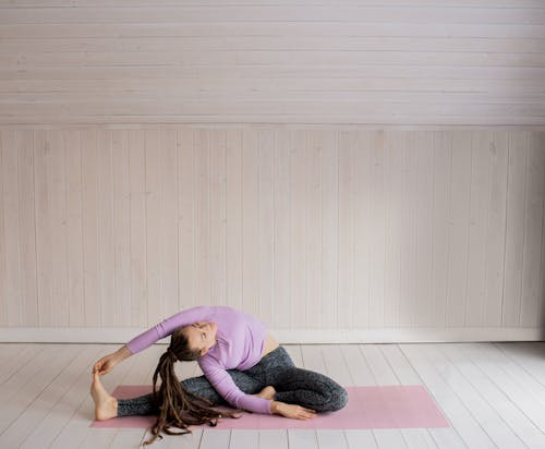 Woman in Purple Long Sleeve Shirt and Black Pants Lying on Floor