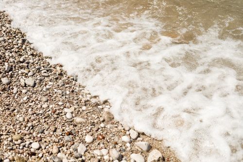 Free Waves gently lapping on a pebble beach, capturing the serene coastal scenery. Stock Photo