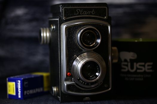 Close-up of a classic twin-lens reflex camera with film boxes.