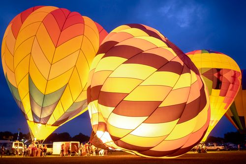 Free Picturesque scenery of colorful vibrant hot air balloons being prepared to launch in dark night sky Stock Photo