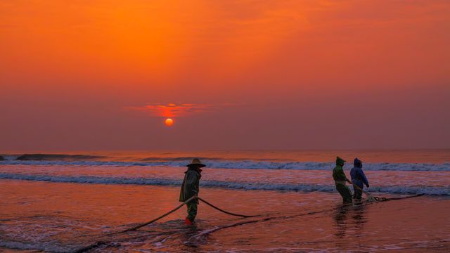 Fishermen pulling nets along the beach at sunrise in Zhanjiang, China, creating a vivid and serene seaside scene. — lounges at Zhanjiang Airport