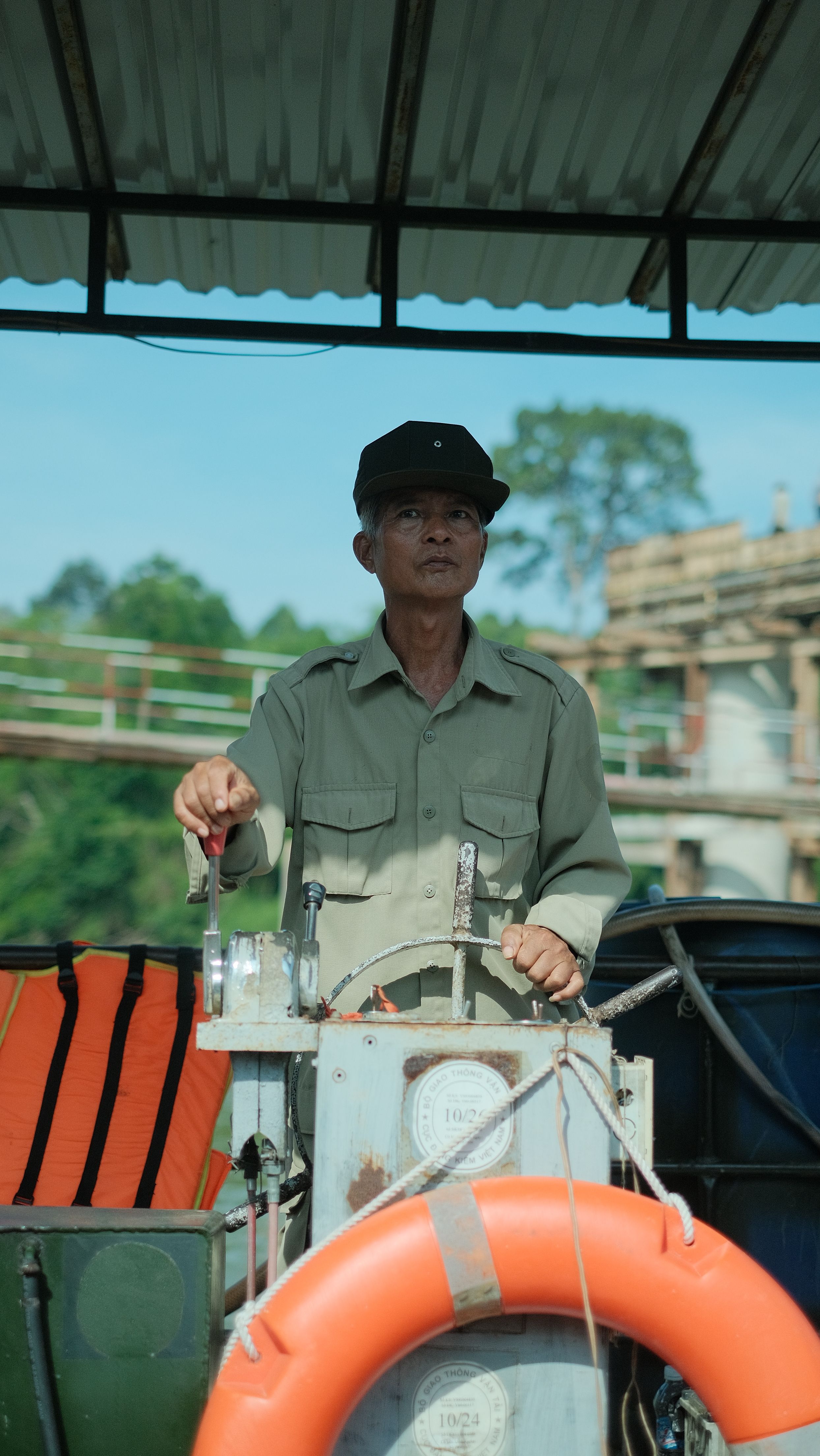 Elderly boat captain steering vessel with life buoy on a sunny day.