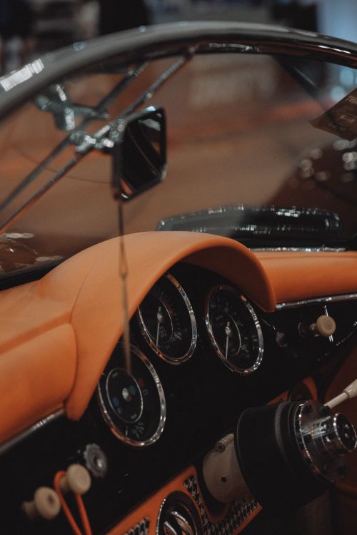 Free Close-up of a vintage car's dashboard with orange leather and classic instruments, capturing nostalgia. Stock Photo