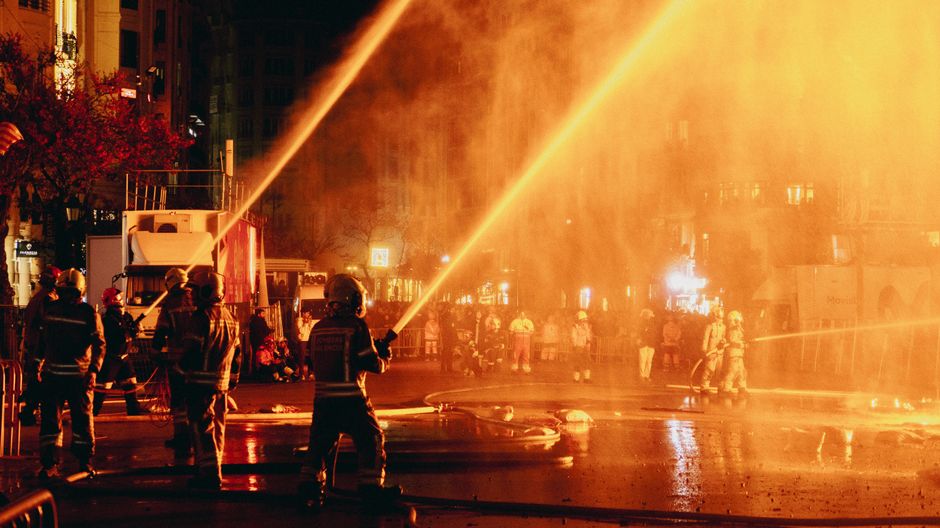 Los bomberos de Valence rocían agua durante un animado festival nocturno, realzando el dramatismo de la escena.