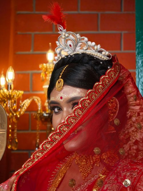 Free Stunning portrait of a traditional Bengali bride wearing a red saree and ornate jewelry. Stock Photo