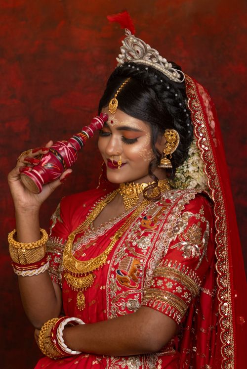 Free South Asian woman in red bridal attire and gold jewelry, symbolizing cultural richness. Stock Photo