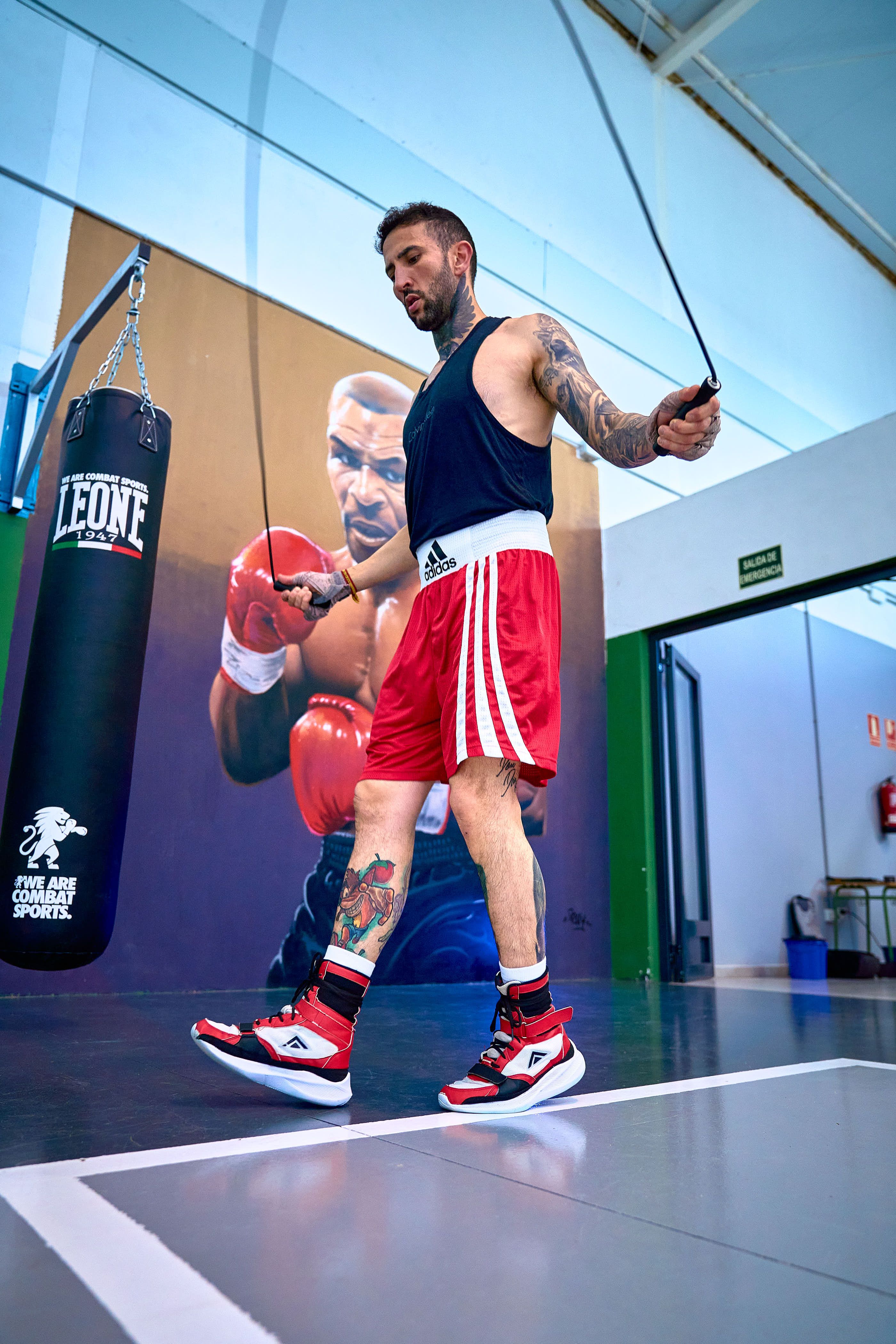 Male athlete jump roping in gym with boxing gear and mural in Valladolid, Spain.